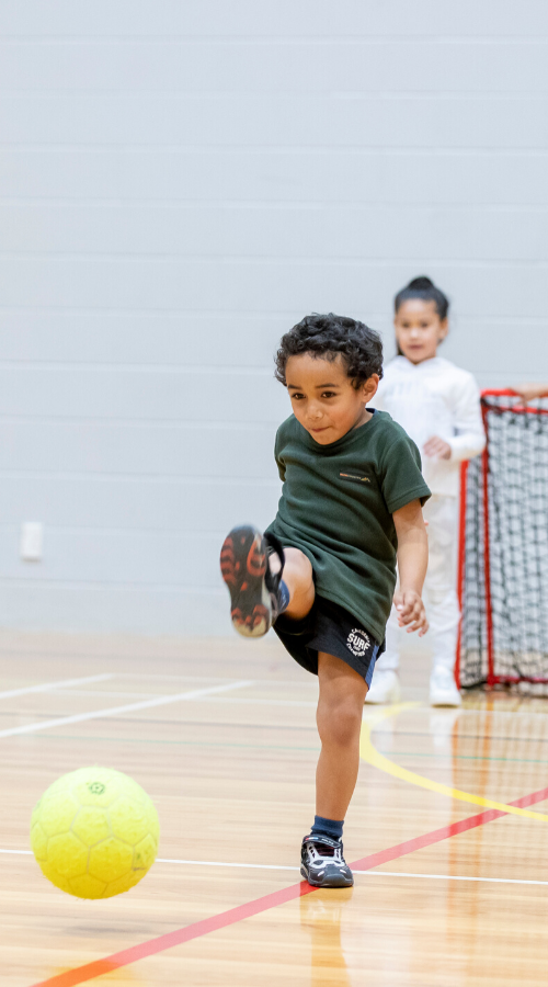 Side image boy kicking ball in stadium